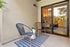 Chic outdoor patio featuring two modern chairs and a small table, seamlessly connected to a cozy bedroom through sliding glass doors.