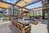 Chic outdoor lounge area featuring modern wooden seating, stylish black and blue cushions, and a spacious patio under shaded pergolas.