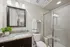 Elegant bathroom with a modern glass shower, granite countertop, and stylish mirror, creating a sophisticated and welcoming ambiance.