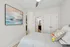 Elegant bedroom with modern art, soft bedding, and a view into a sleek bathroom with contemporary fixtures.