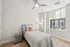 Bright and cozy bedroom with modern decor, featuring elegant bedding, a stylish ceiling fan, and abundant natural light from a large window.