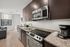 Modern kitchen with sleek dark cabinets, stainless steel appliances, and granite countertops adjacent to a cozy living area with natural light.