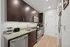 Sleek modern kitchen with dark wood cabinetry, granite countertops, and stainless steel appliances, accentuating a contemporary apartment style.