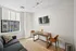 Bright and modern dining nook with sleek furnishings, featuring a chic wooden table set for two and a cozy sofa near a sunlit window.