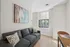 Bright and modern living space featuring a chic gray sofa, abstract wall art, and a sunlit window with a stylish blue vase.