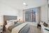 Bright, cozy bedroom with modern decor, featuring a plush grey bed, large window with city views, and elegant side table lamps.