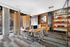 Modern office space with sleek wooden desks, ergonomic chairs, and stylish interior decor featuring a brick wall and large windows offering natural light.