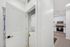 Modern apartment laundry space with a stacked washer and dryer, next to a sleek kitchen featuring stainless steel appliances and ample cabinetry.
