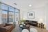 Bright and inviting living room with large windows, modern decor, and cozy seating, perfect for relaxation and city views.