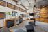 Chic and cozy lounge area with modern open shelving, inviting seating, and stylish lighting. Features a mini-fridge and wooden accents that enhance the contemporary feel.