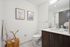 Modern bathroom with elegant decor, featuring wooden vanity, stylish artwork, and natural lighting.