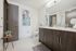 Modern bathroom with elegant wood-finished cabinetry, sleek dual sinks, and a stylish abstract art piece on the wall creating a contemporary vibe.