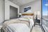 Bright and inviting bedroom with modern decor, featuring a cozy bed, stylish nightstand, and large window offering natural light.