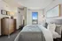 Modern bedroom retreat with elegant wood accents, cozy bed with plush pillows, and a large window offering a breathtaking city view.