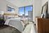 Bright and modern bedroom with a cozy bed, stylish decor, and a large window showcasing a stunning city view.