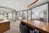 Modern office space with glass-enclosed meeting rooms, elegant wood and neutral furnishings, and natural light.