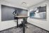 Modern, stylish office nook with adjustable standing desk, sleek monitor setup, and contemporary abstract art enhancing productivity and creativity.