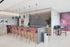 Modern communal kitchen featuring a sleek island with chic red barstools, stylish pendant lighting, and vibrant abstract wall art.