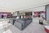 Chic open-concept apartment interior showcasing a stylish lounge area with modern furniture, vibrant wall art, and a sleek bar with contemporary seating.