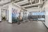 Modern gym facility with vibrant wall art, weight bench, free weights, and mirrored walls for an energetic workout environment.