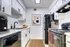 Contemporary apartment kitchen with sleek white cabinets, black appliances, and stylish decor.