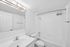 Bright and modern bathroom featuring a sleek white vanity, contemporary lighting, and a pristine bathtub with shower.