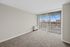 Bright and airy room with plush carpeting, large windows with vertical blinds, and a stunning city view.