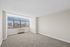 Bright and spacious room with plush carpeting and expansive city views through large windows.