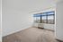 Bright and inviting bedroom with large windows offering panoramic city views. Features plush carpeting and ample natural light, perfect for a relaxing retreat.