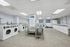 Spacious and modern laundry room with multiple washers and dryers, bright lighting, and ample folding space.