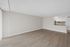 Spacious living area with modern wood flooring and an open-plan kitchen with sleek cabinetry and backsplash.
