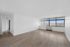 Bright and spacious living room with large windows offering a stunning city view, complemented by elegant hardwood floors.