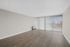 Bright and spacious living area with elegant hardwood flooring and large windows offering stunning city views.
