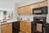 Inviting kitchen featuring modern black appliances, warm wooden cabinetry, and a sleek white countertop with stylish decor.