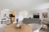 Chic open-concept living room with stylish decor and modern kitchen featuring sleek cabinetry and breakfast bar.