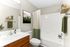 Inviting modern bathroom with elegant wooden vanity, lush green accents, and serene nature artwork.