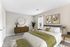 Elegant bedroom with modern decor, featuring a plush bed, artistic wall art, and a cozy seating area.