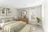 Bright and airy bedroom with elegant wooden furniture, lush green bedding, and contemporary artwork, offering a serene and inviting atmosphere.