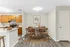 Bright dining area with a stylish round wooden table, modern kitchen appliances, and warm cabinetry, perfect for cozy home dining.