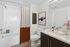 Modern bathroom with elegant white fixtures, a sleek vanity, and vibrant art adding a touch of color.