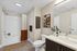 Modern bathroom with elegant decor, featuring sleek vanity, stylish artwork, and earthy tone shower curtain.