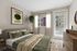 Modern bedroom featuring a plush bed with green and beige accents, chic artwork, and natural light illuminating from large windows with sheer curtains.