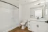 Modern bathroom featuring sleek white cabinetry, elegant marble countertops, and a spacious bathtub with chic black fixtures.