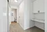 Bright hallway leading to a modern bathroom with plush carpet, marble countertop workspace, and ample storage cabinets.