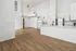 Bright and airy open-plan apartment featuring sleek white cabinetry, stainless steel appliances, and elegant wooden flooring.
