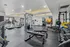 Modern gym with state-of-the-art equipment, including treadmills, weight machines, and free weights, accented by vibrant artwork and ample natural light.