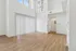 Bright, spacious living area with beautiful wood flooring, high ceilings, and large windows for natural light.