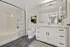 Modern and inviting bathroom featuring sleek white cabinetry, elegant marble countertop, and a stylishly patterned shower curtain.