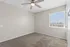 Bright and airy bedroom featuring plush carpeting and a ceiling fan, enhanced by natural light from a large window.