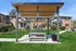 Inviting outdoor space with modern pergola, sleek barbecue area, and lush green surroundings in a charming residential community.